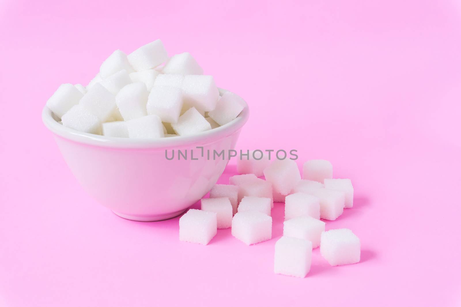 Closeup sugar cubes on bowl with pink background, health care concept