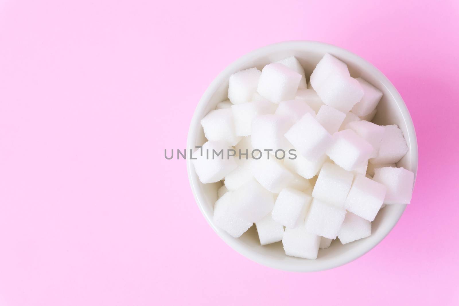 Closeup sugar cubes on bowl with pink background, health care concept