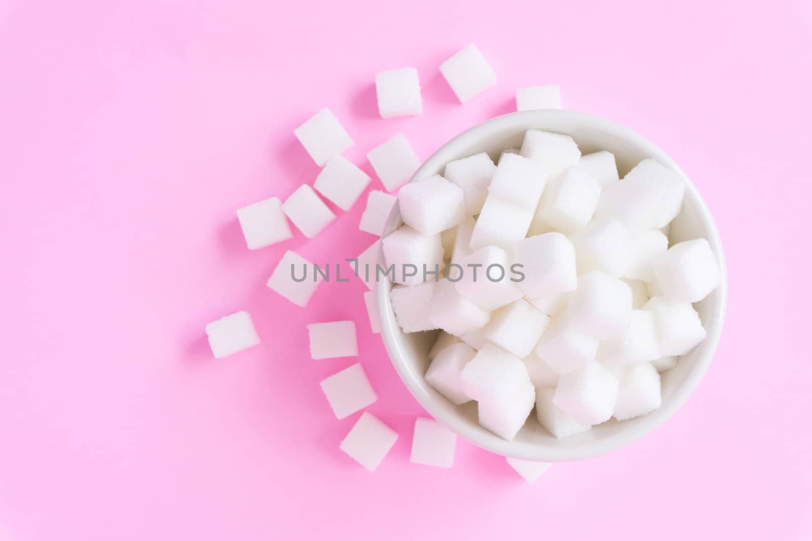 Closeup sugar cubes on bowl with pink background