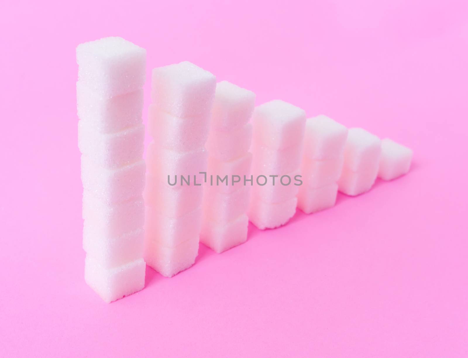 High to low stacks of sugar cubes with pink background, health care diet concept
