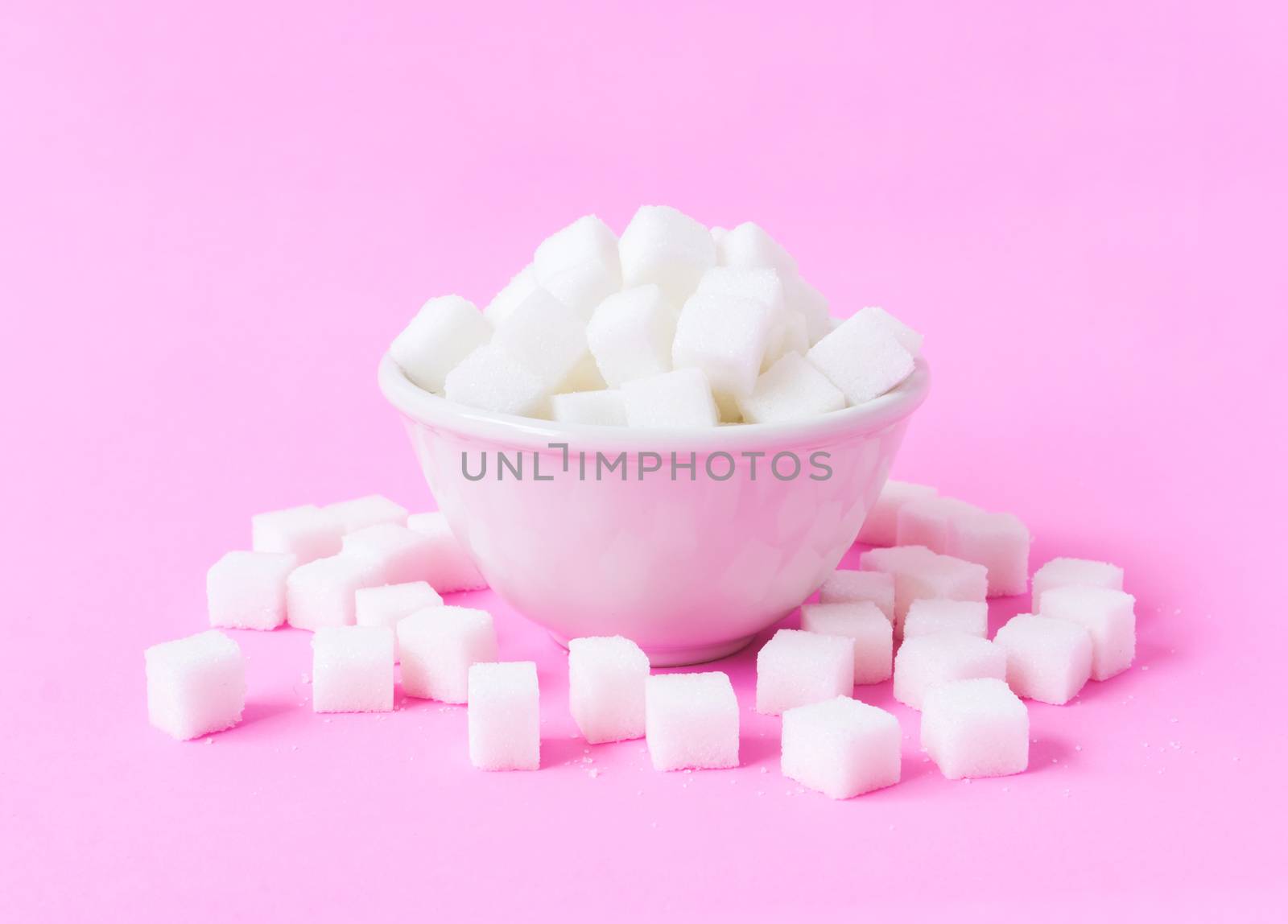 Closeup sugar cubes on bowl with pink background, health care concept