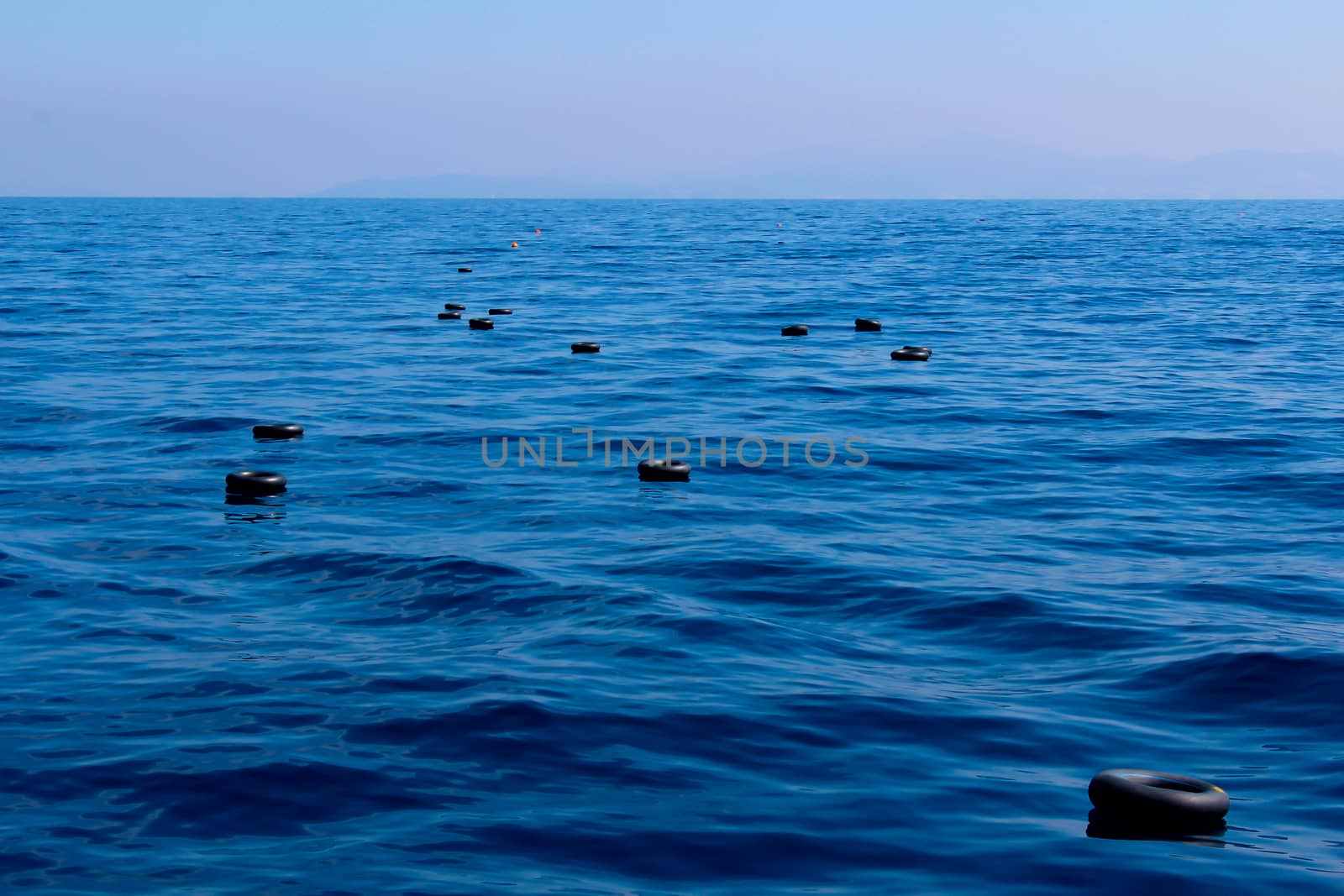 Inner tubes of car tires and life vests floating in the Mediterranean sea, used by a boat of refugees for flotation