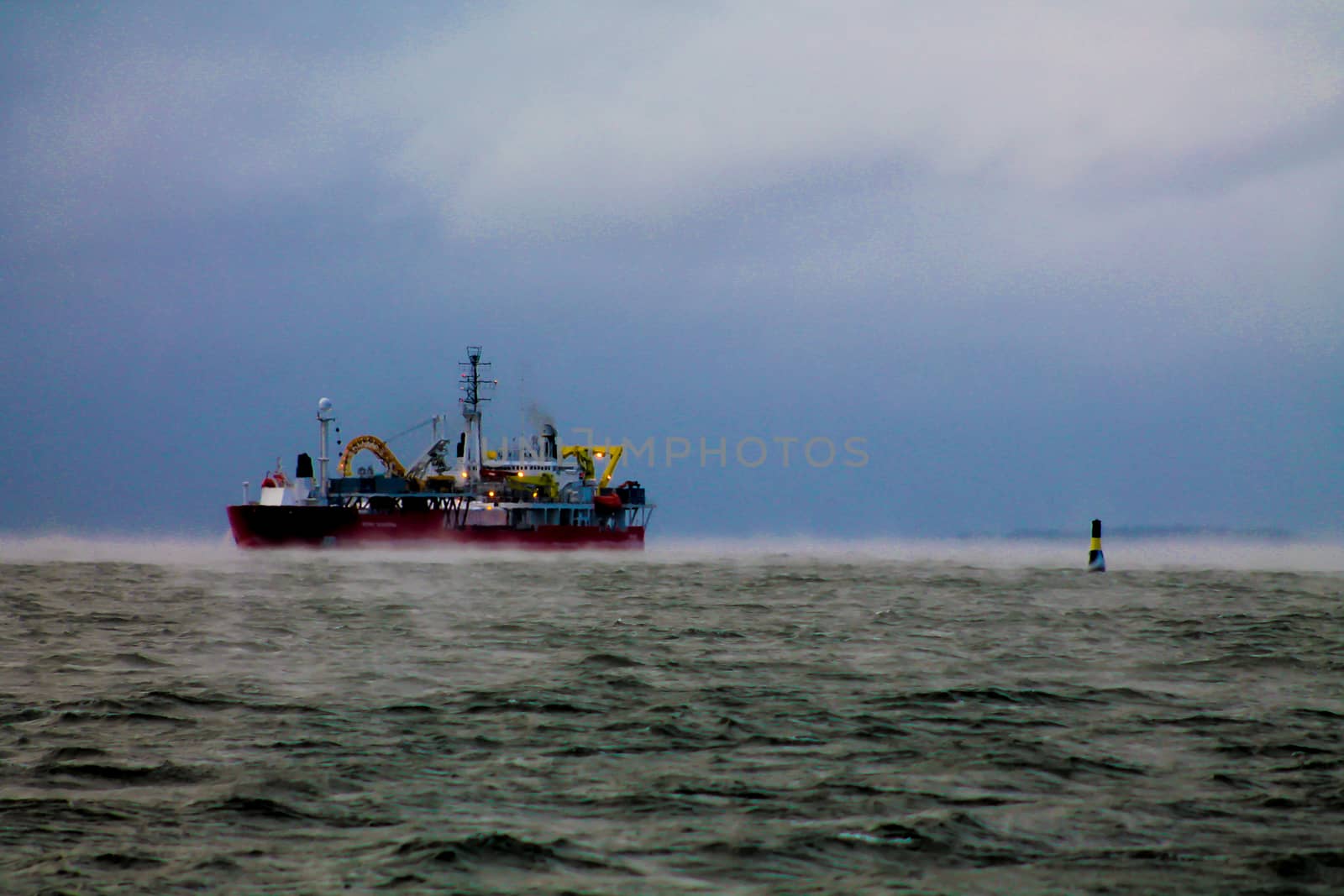 A cable ship and a navigational buoy in a hazy sea