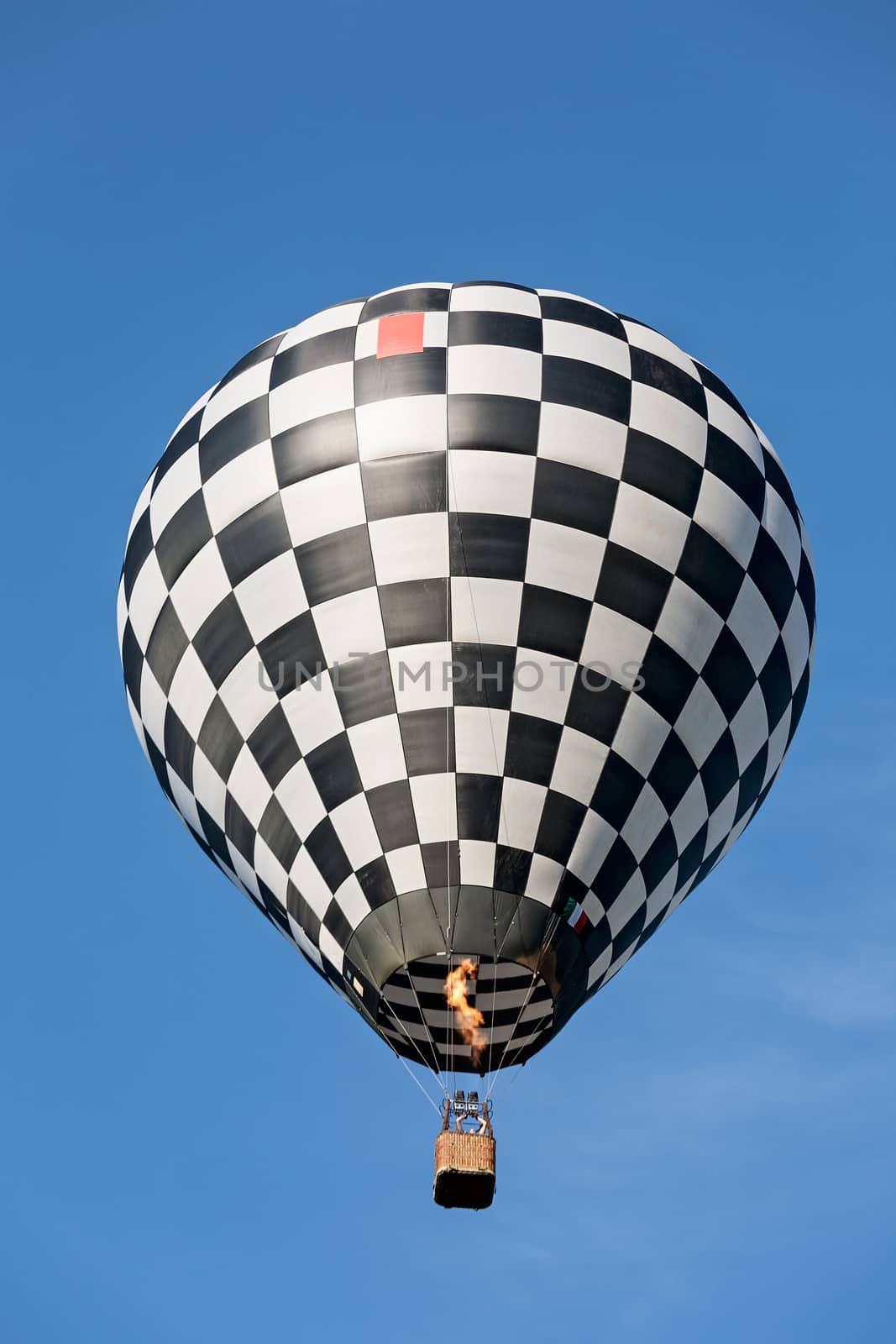 Black and white balloon in flight against a blue sky