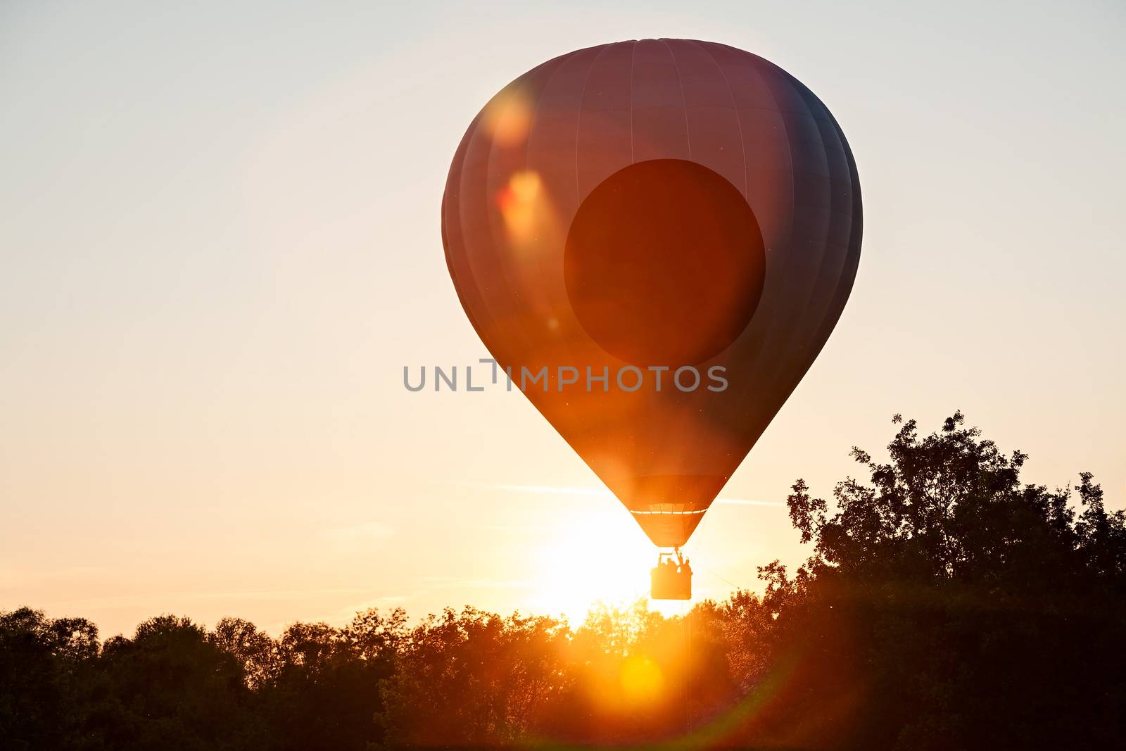 Hot-air balloon in silhouette ready to get up in flight against the sun