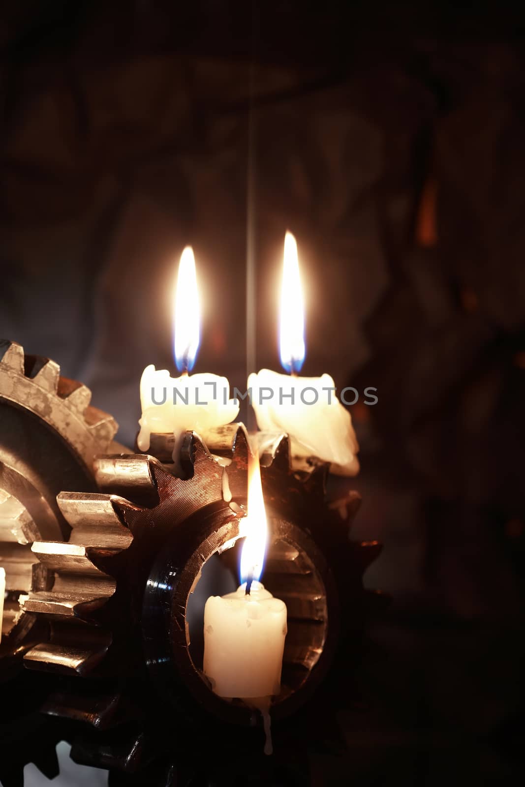 Lighting candles on old gears against dark background