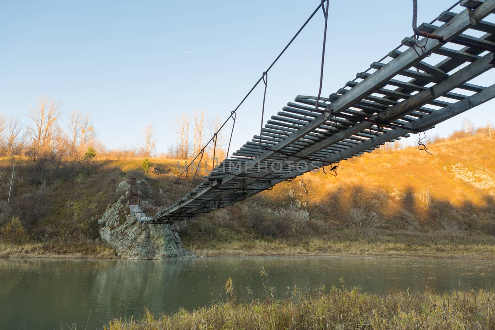 The old hanging footbridge across a small river.