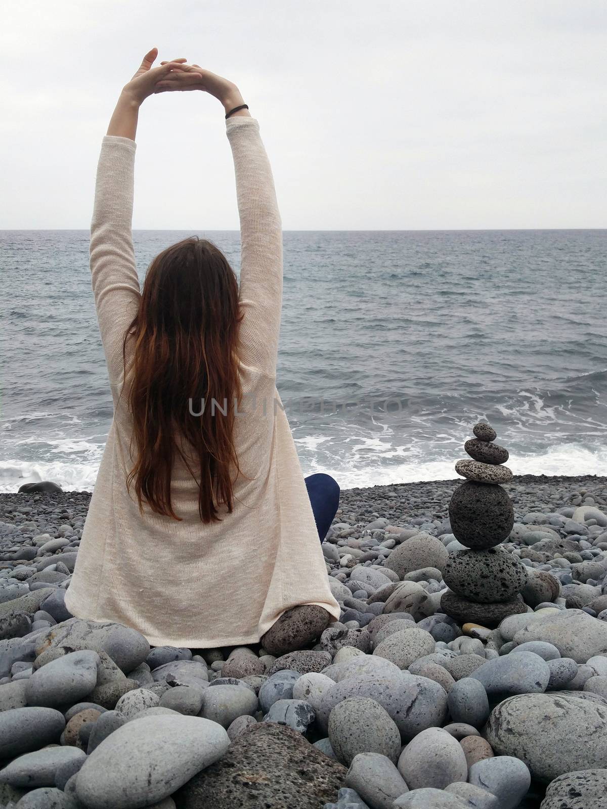 girl stretching arms in pebble beach in Madeira island, Portugal.