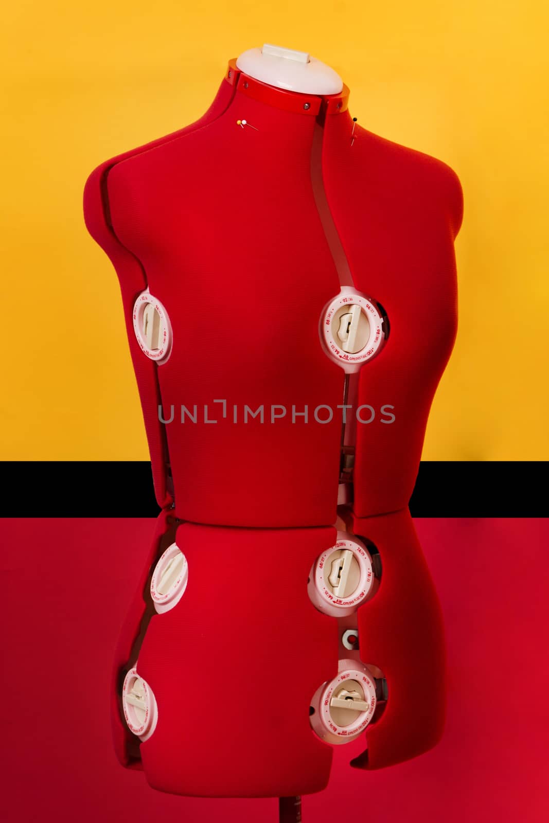 Close view of a red dressmaker dummy over a colorful background.