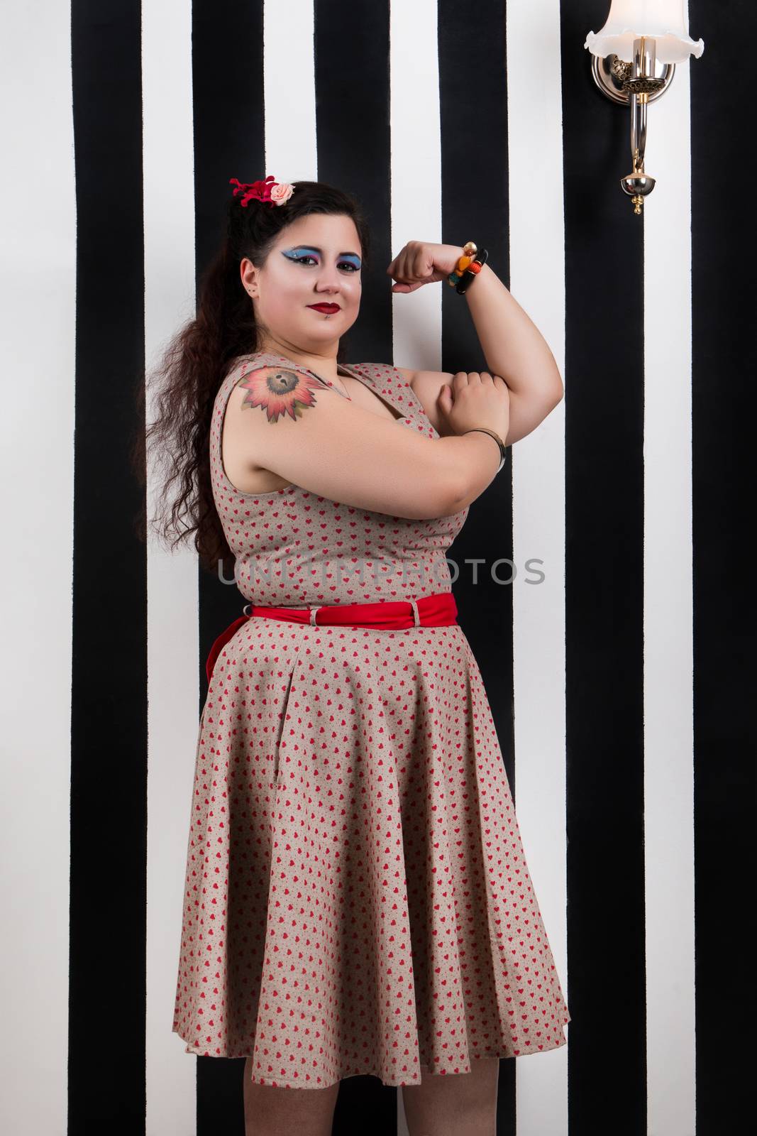 Pinup girl posing on a stripes backdrop by membio