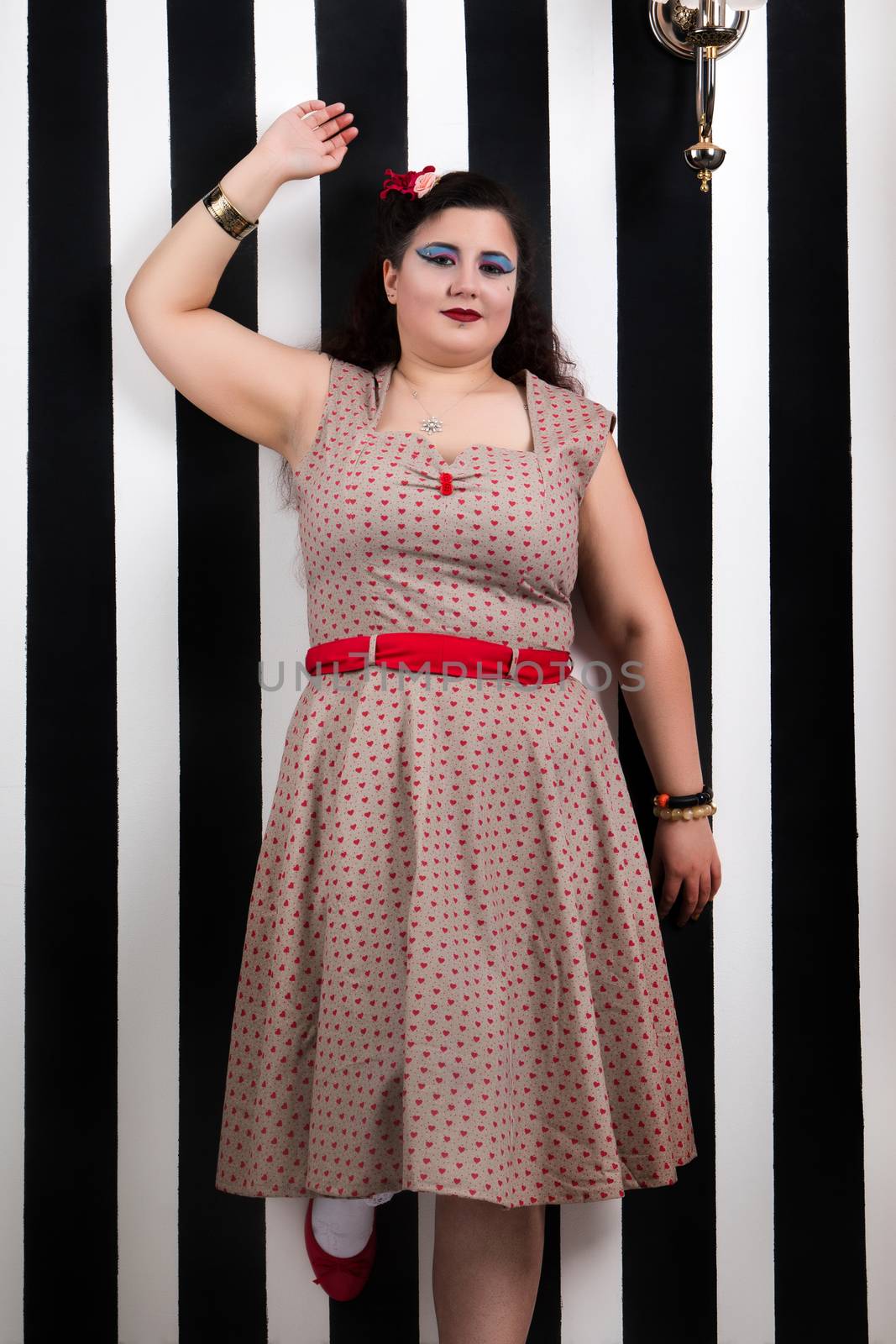 Pinup girl posing on a black and white stripes backdrop.