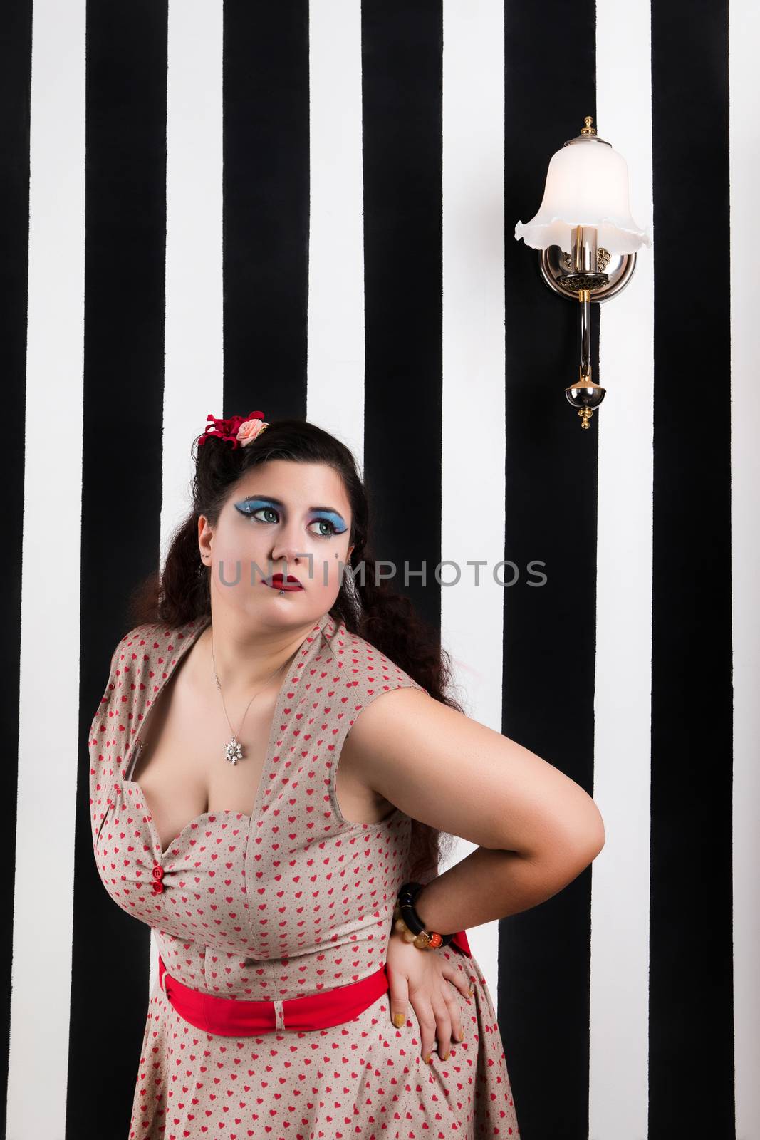 Pinup girl posing on a black and white stripes backdrop.