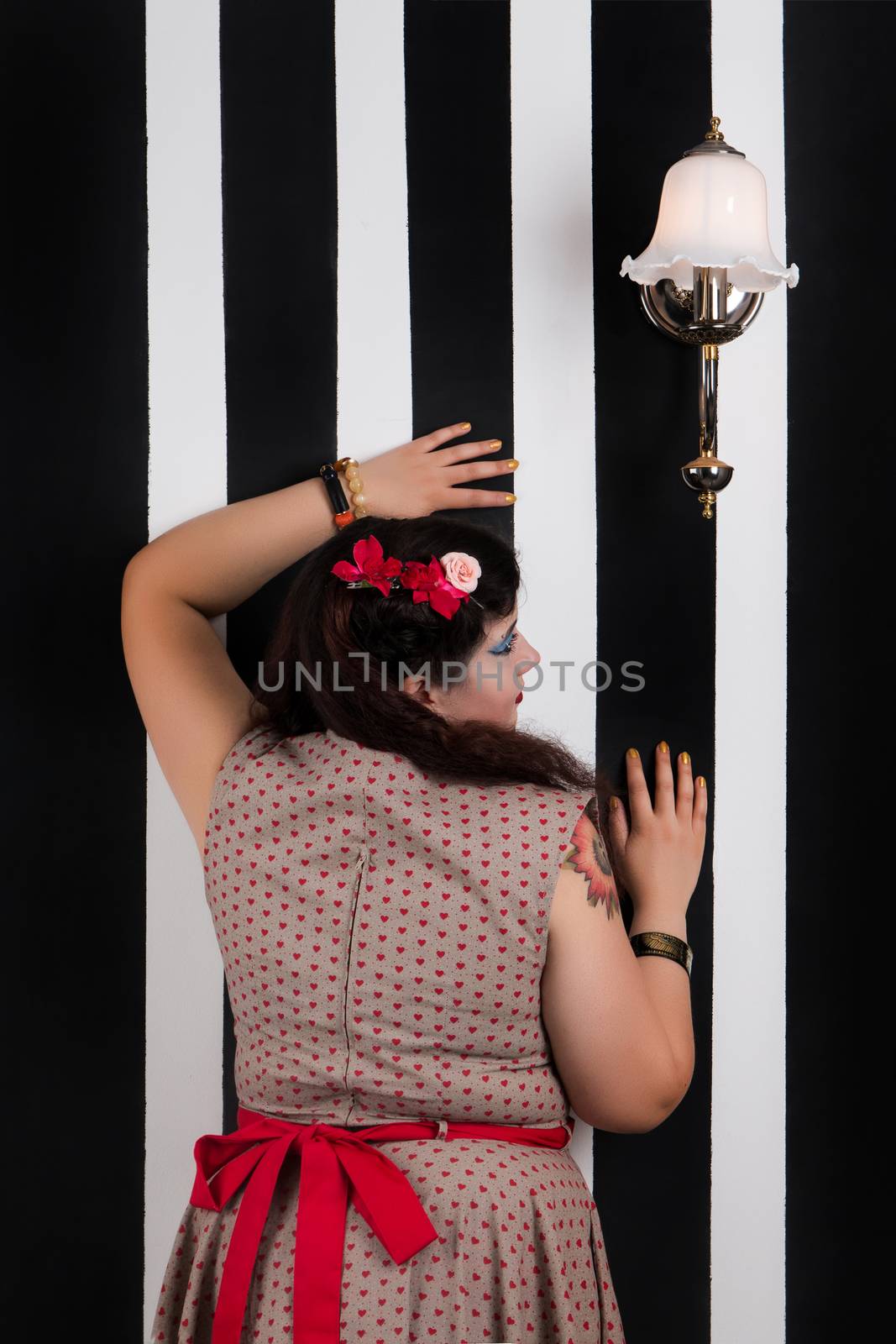 Pinup girl posing on a black and white stripes backdrop.