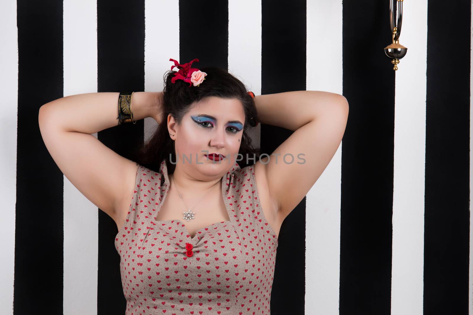 Pinup girl posing on a black and white stripes backdrop.