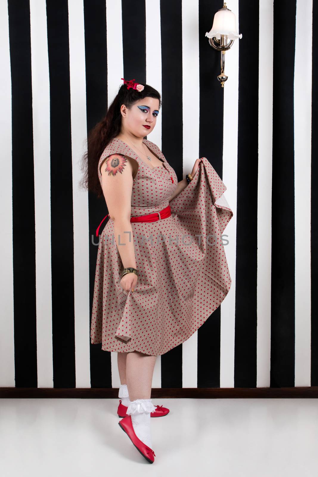 Pinup girl posing on a black and white stripes backdrop.