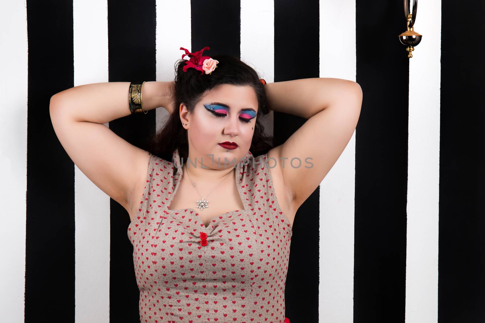 Pinup girl posing on a black and white stripes backdrop.