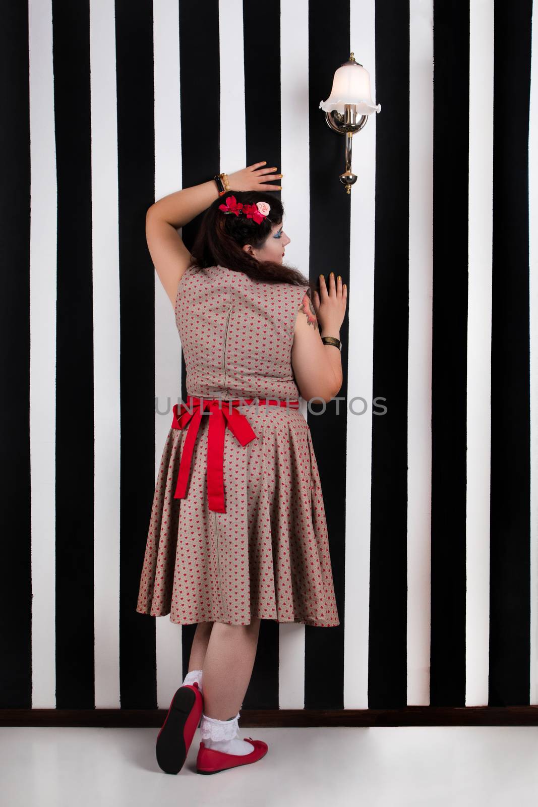 Pinup girl posing on a black and white stripes backdrop.