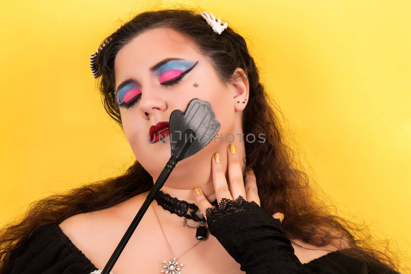 View of pinup vintage girl next to yellow backdrop teasing fetish.