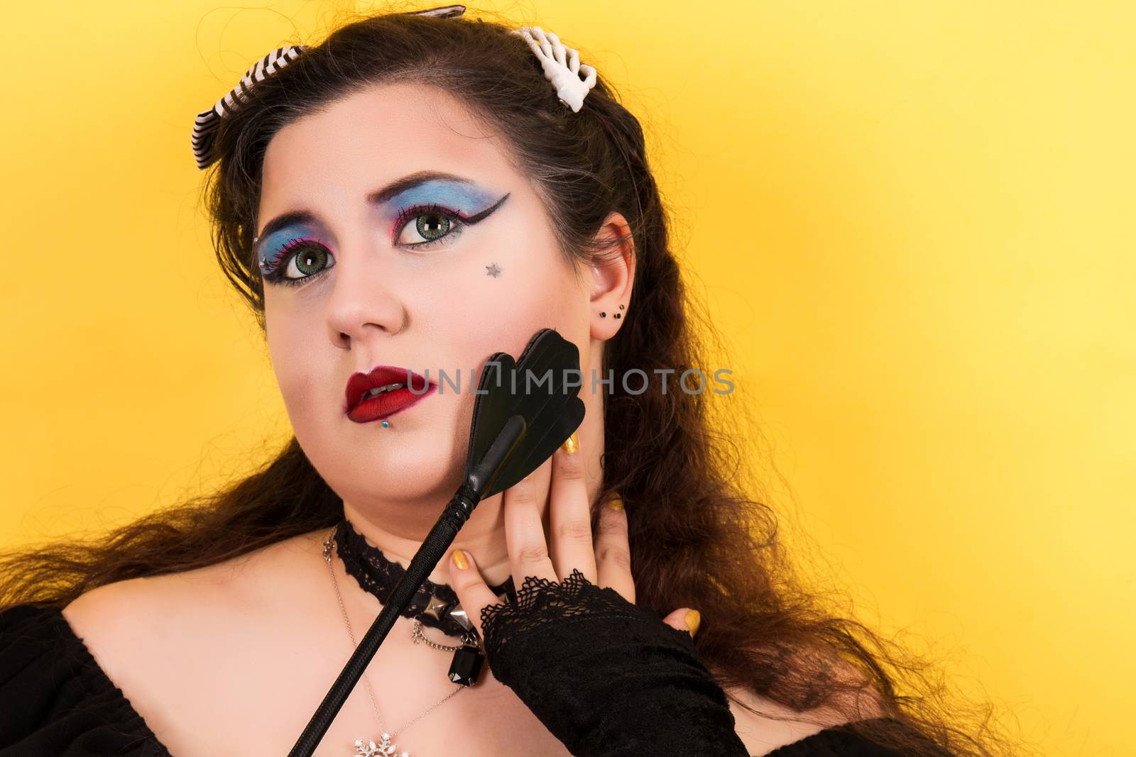 View of pinup vintage girl next to yellow backdrop teasing fetish.