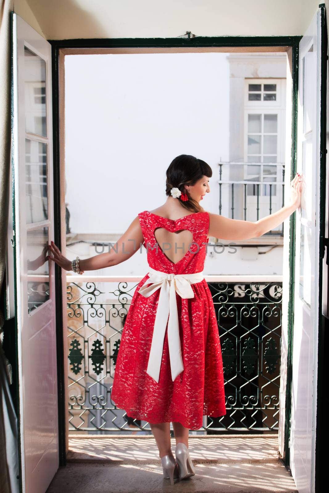 Pinup girl with red dress next to a classic window.