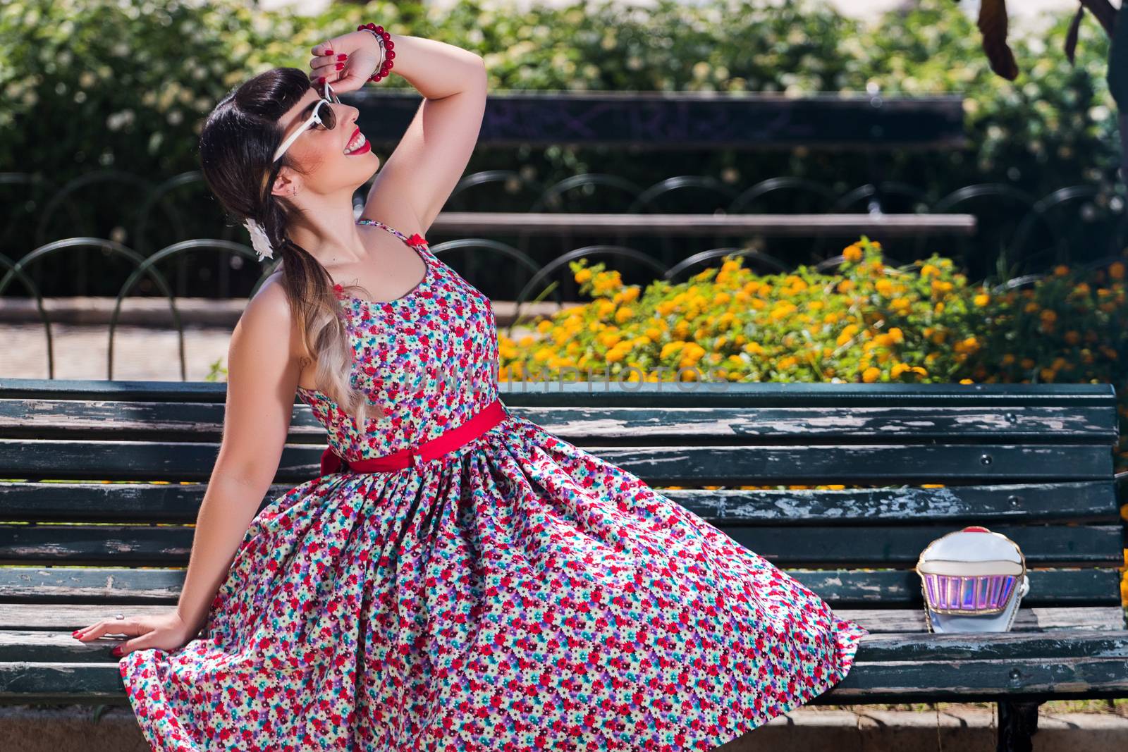 Pinup girl  with dress relaxing in the beautiful urban park.