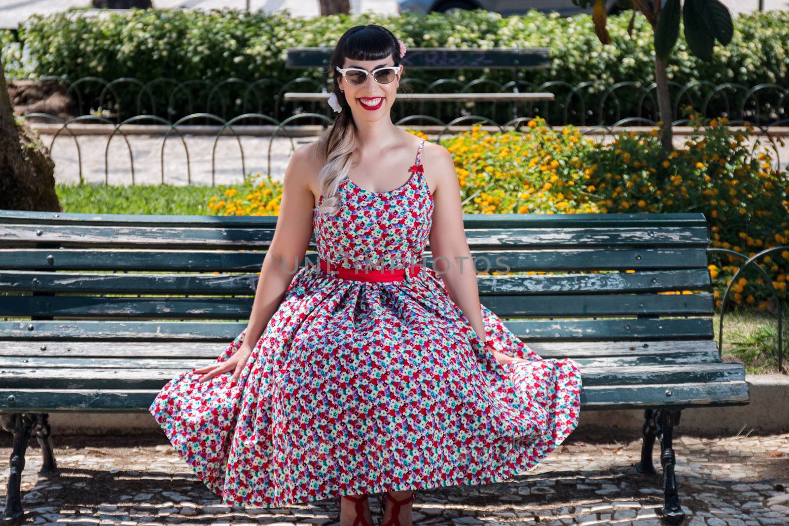 Pinup girl  with dress relaxing in the beautiful urban park.