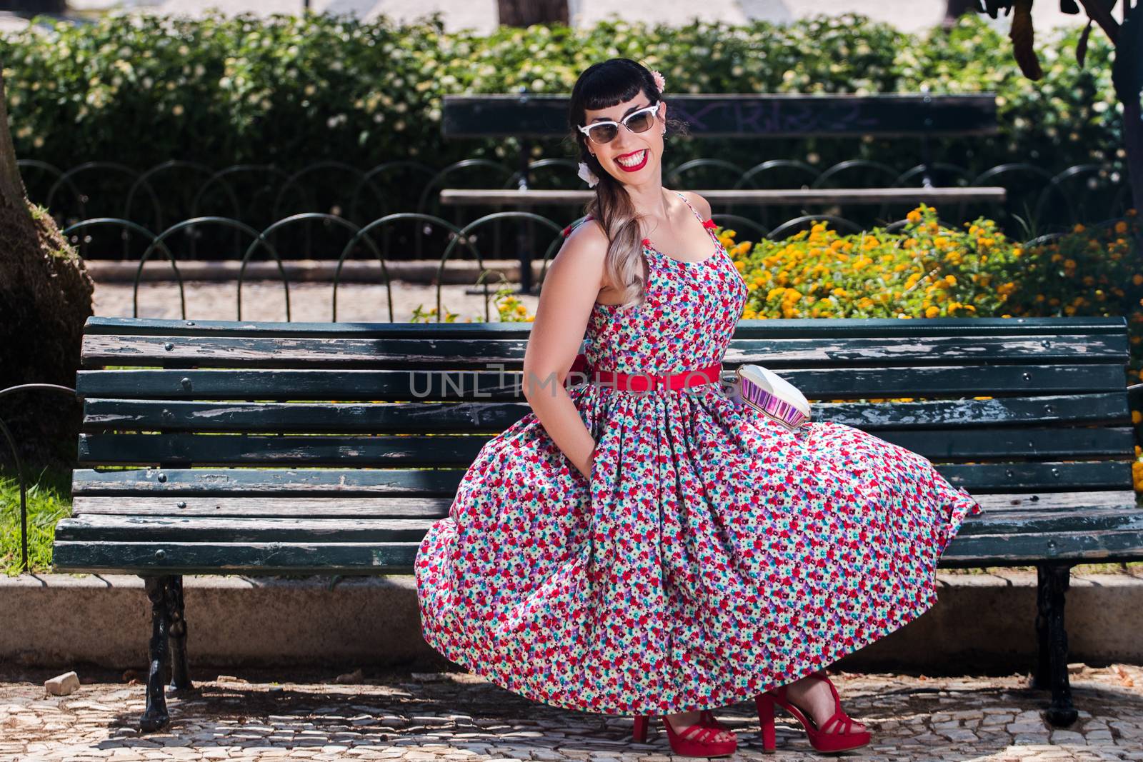 Pinup girl  with dress relaxing in the beautiful urban park.