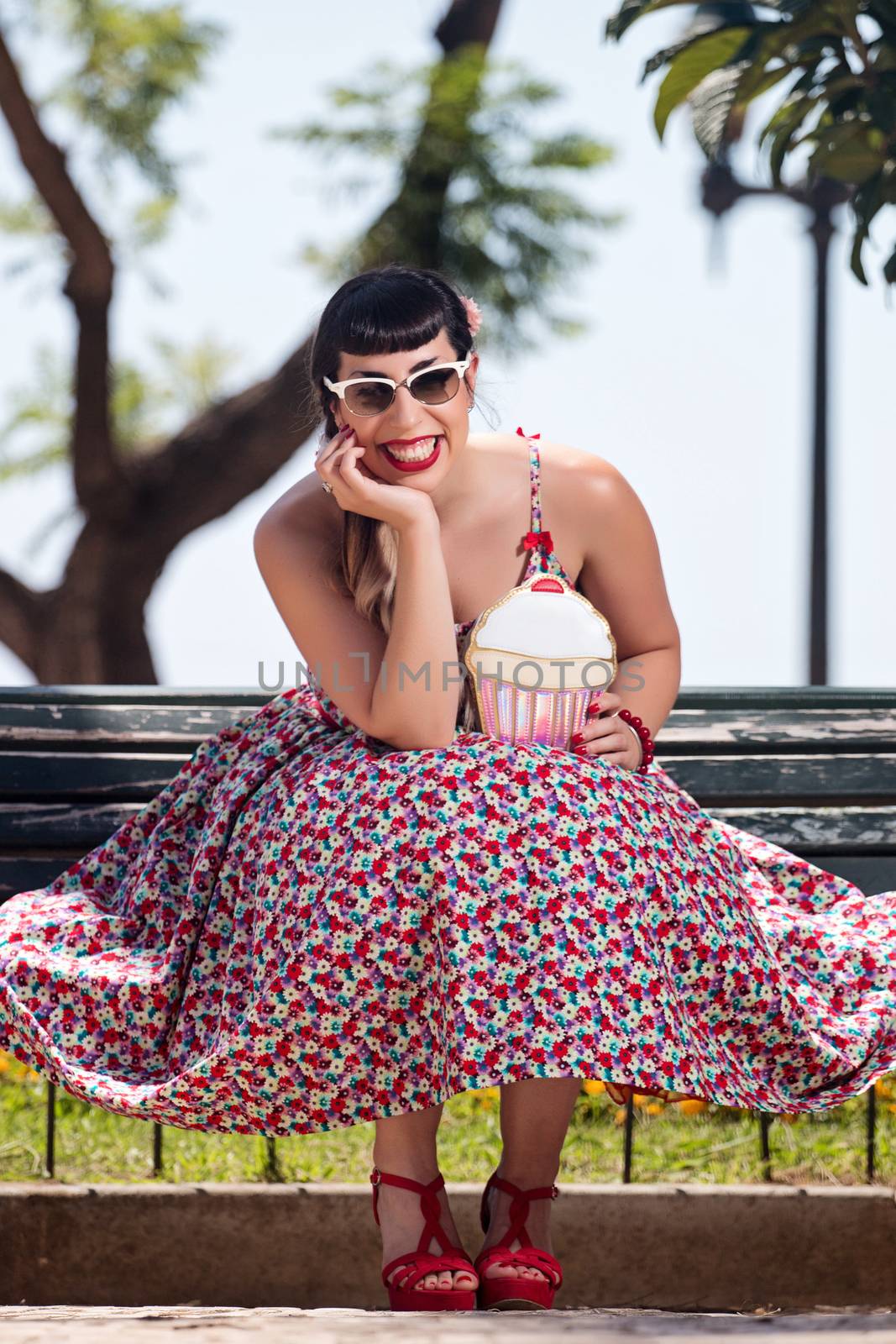 Pinup girl  with dress relaxing in the beautiful urban park.