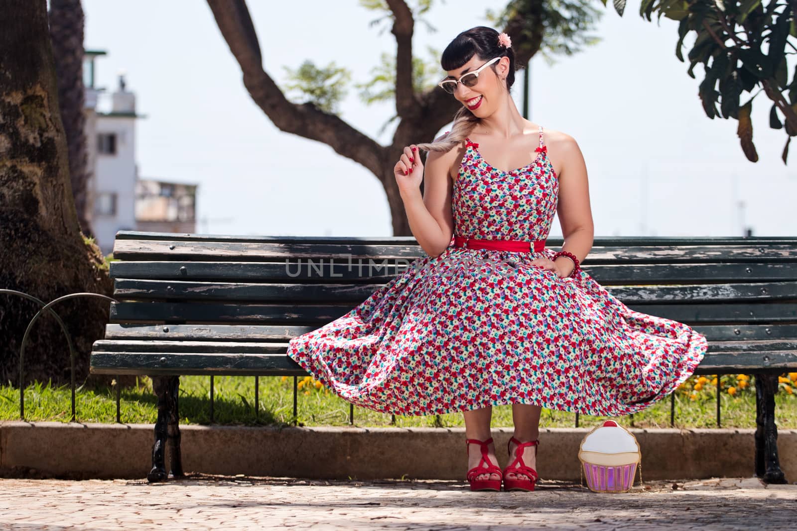 Pinup girl  with dress relaxing in the beautiful urban park.