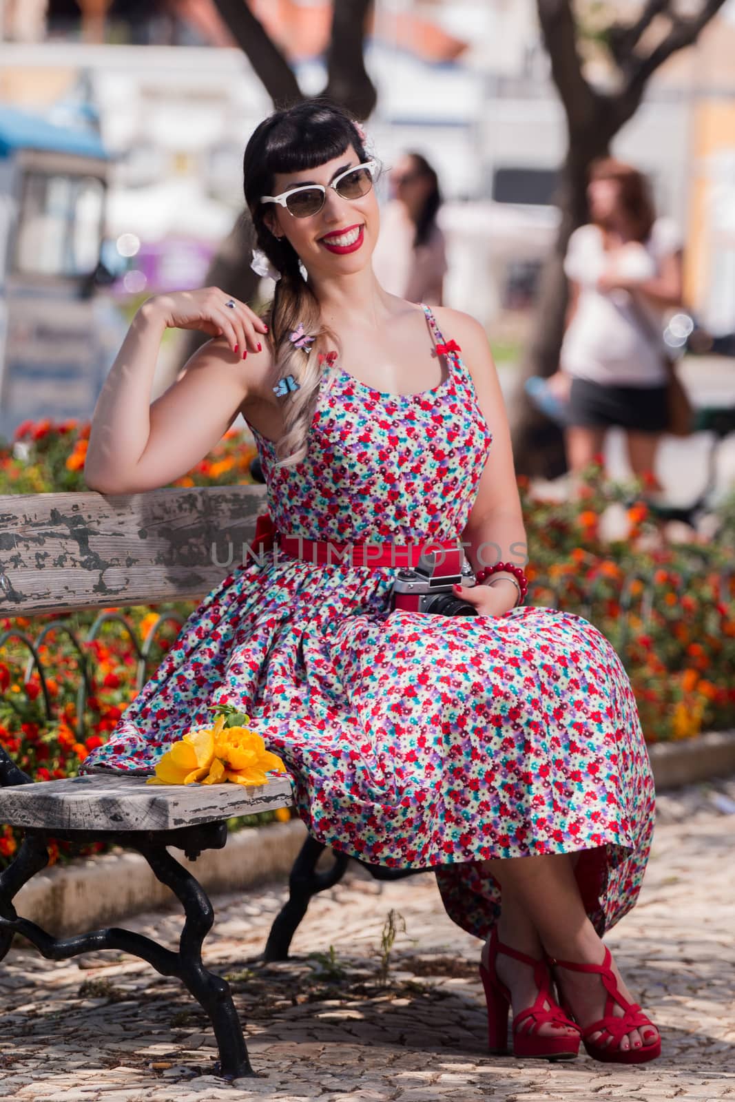 Pinup girl  with dress relaxing in the park, using a vintage camera.