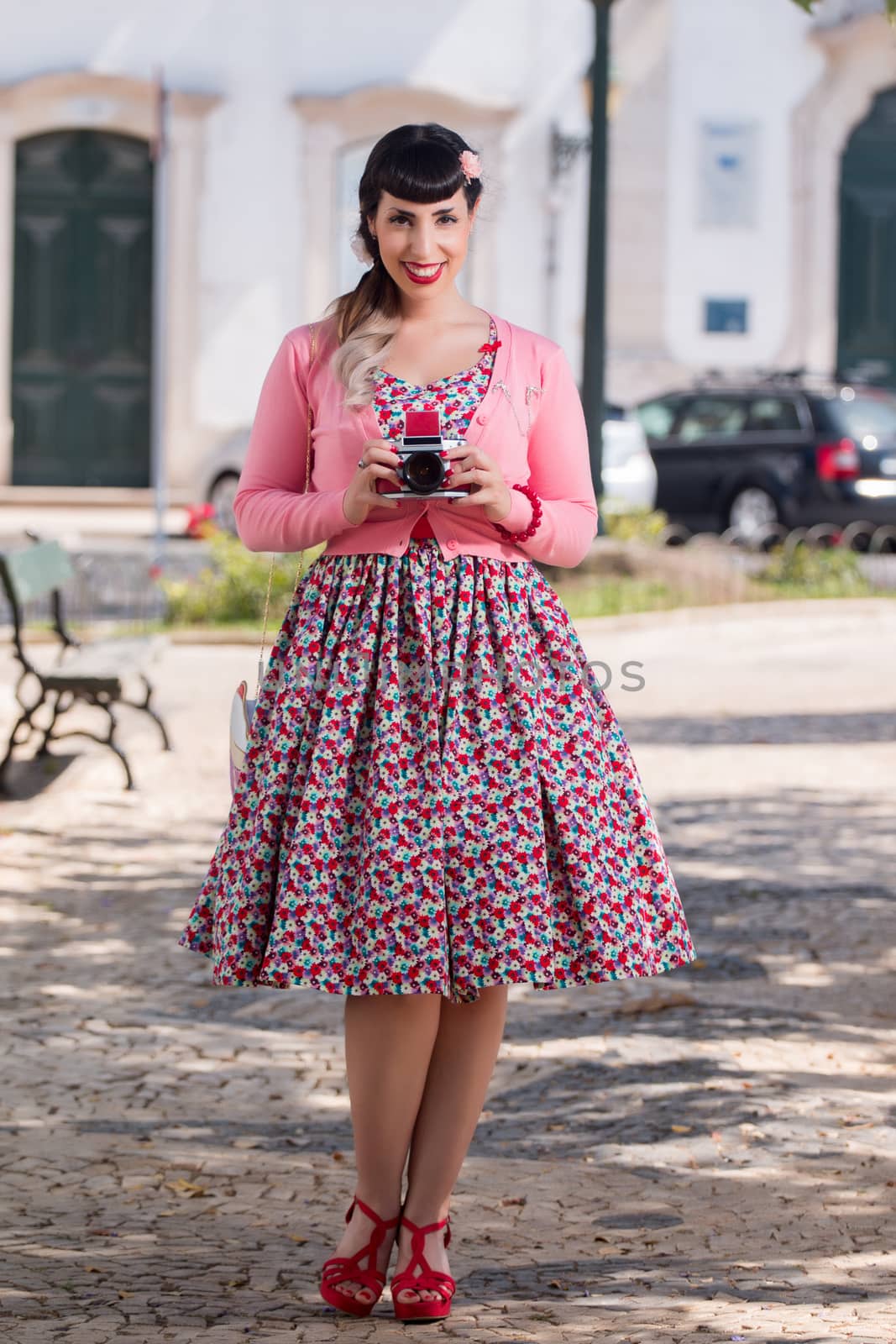 Pinup girl using a vintage camera in a urban park.