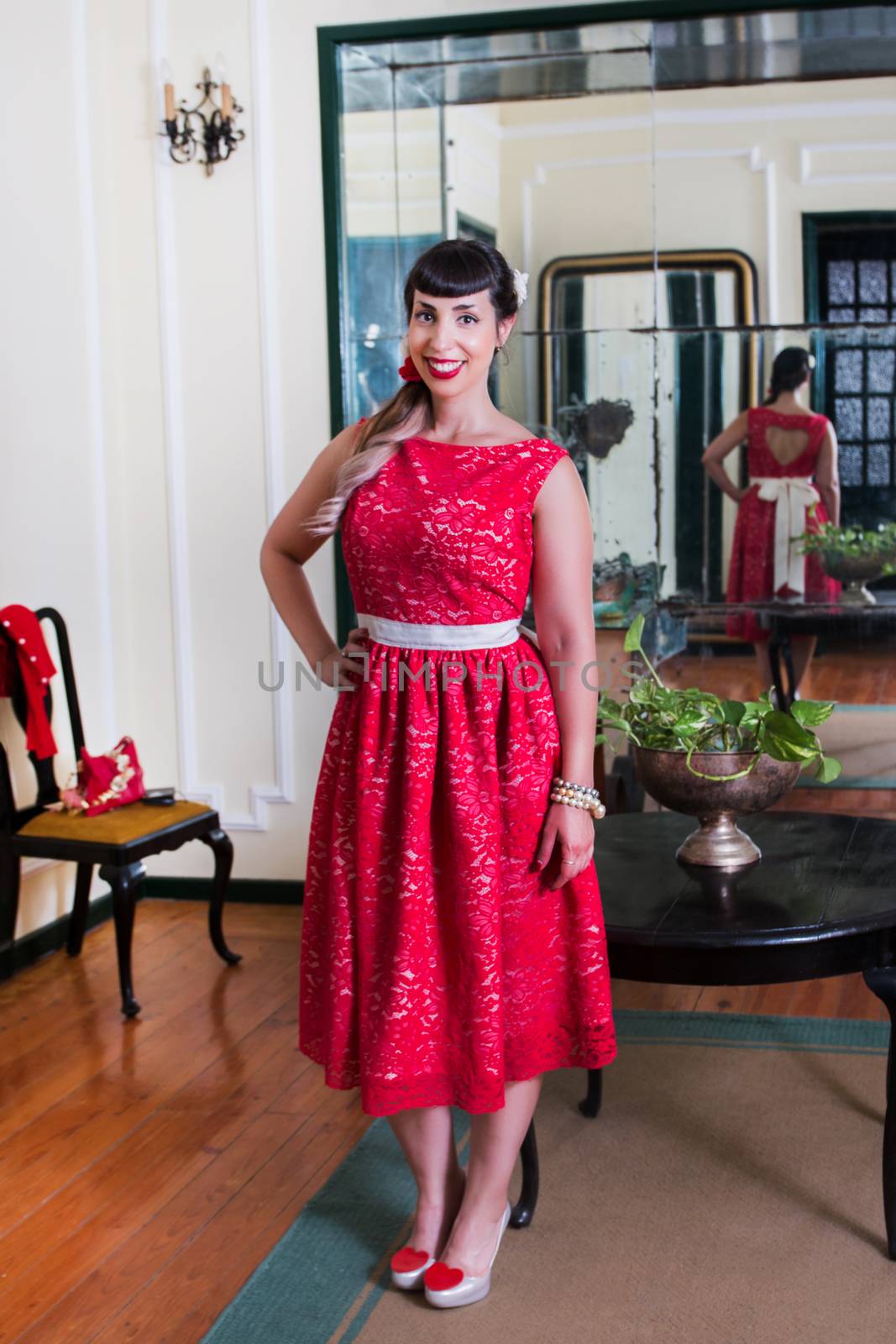 Pinup girl with red dress posing on a vintage home.