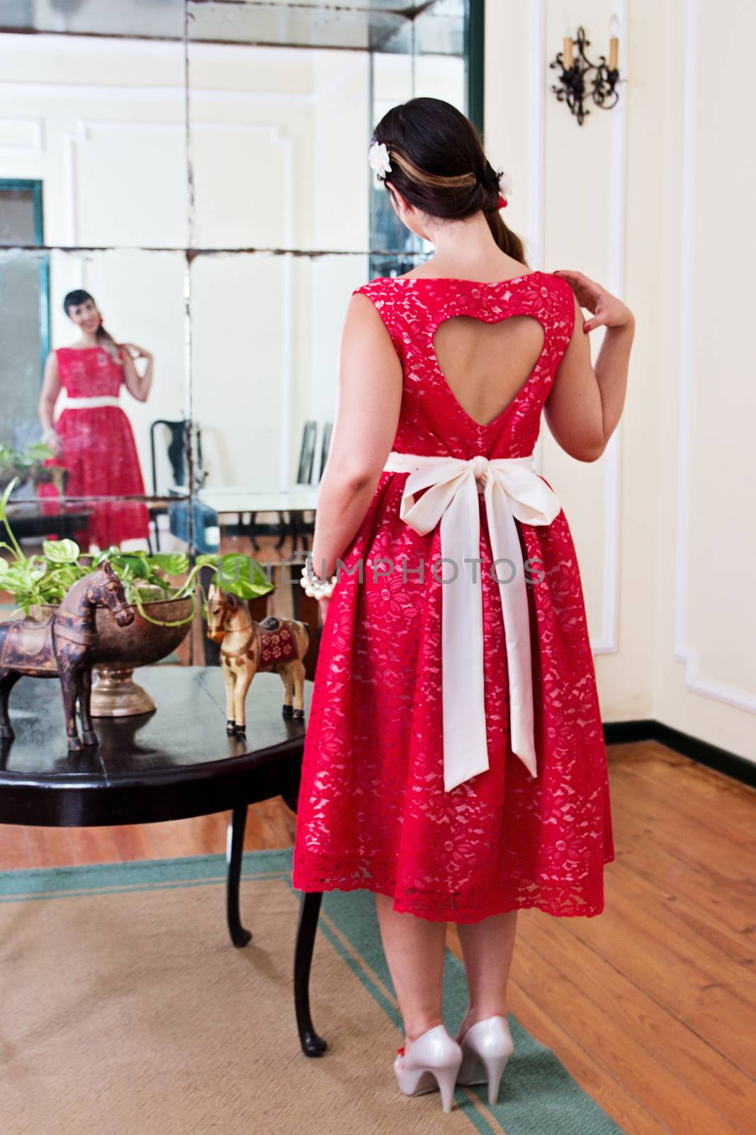 Pinup girl with red dress posing on a vintage home.