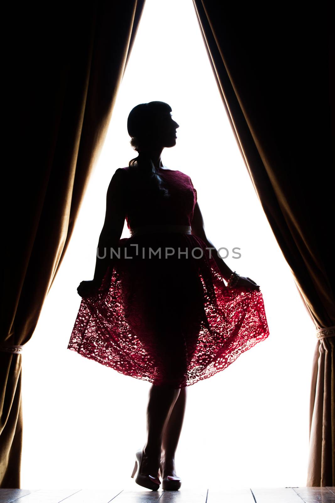 Silhouette of pinup girl with red dress next to a classic window.