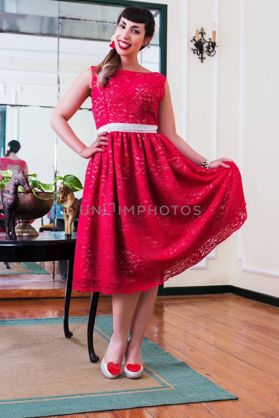 Pinup girl with red dress posing on a vintage home.