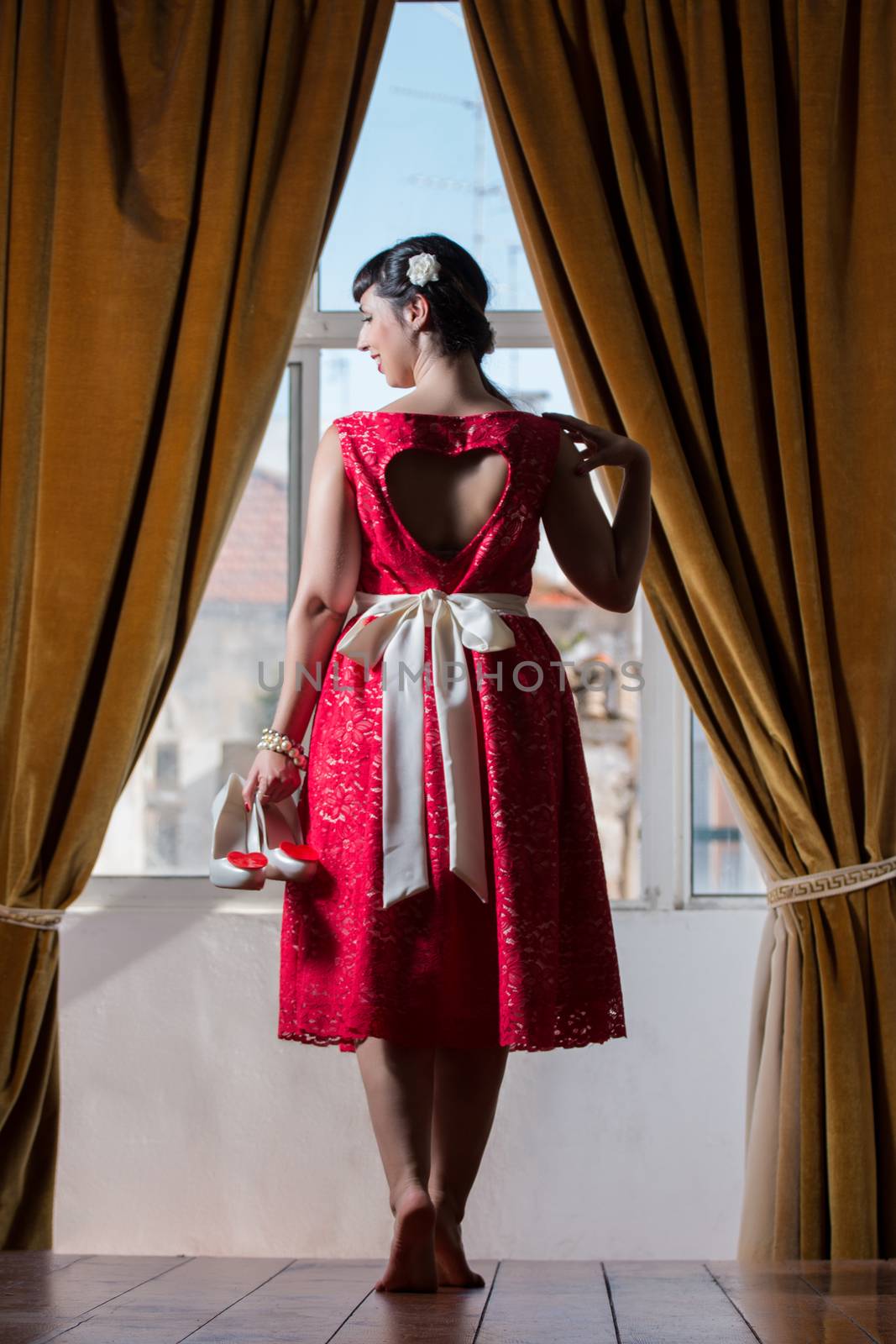 Pinup girl with red dress next to a classic window.