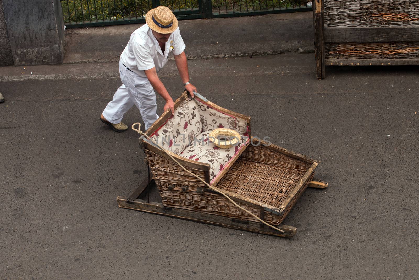 Traditional toboggan man operating a wicker basket car.