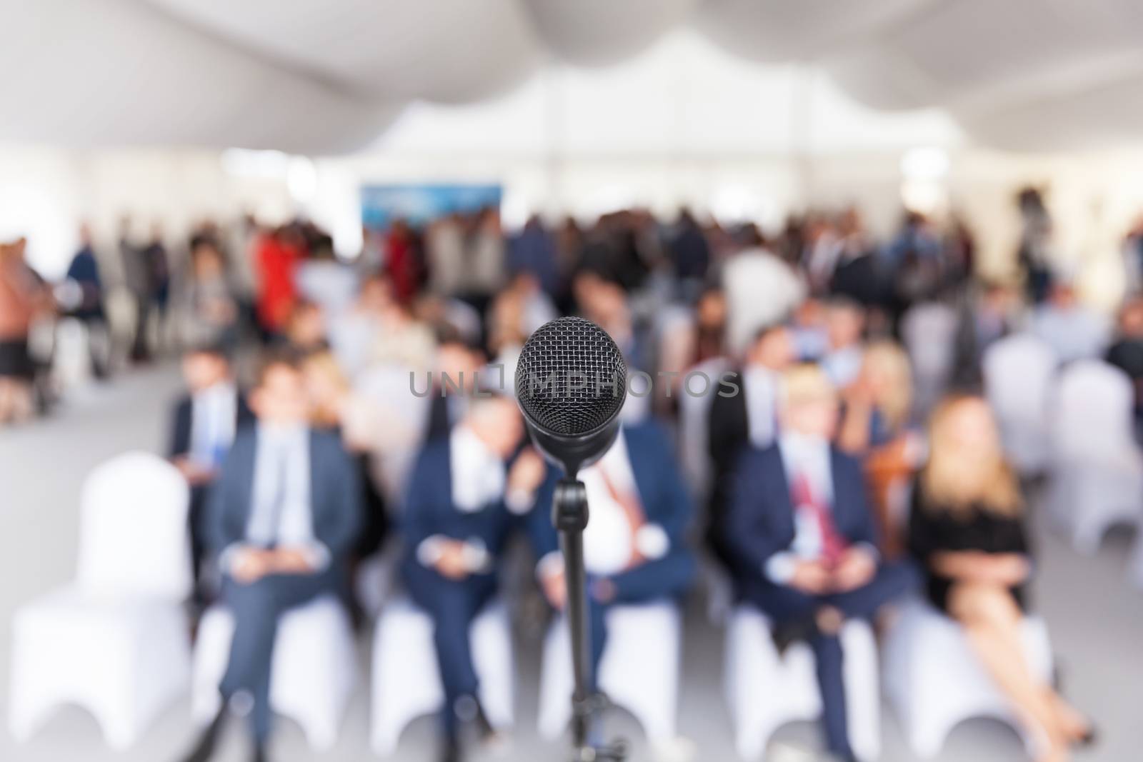 Microphone in focus against blurred audience. Participants at the business or professional conference.