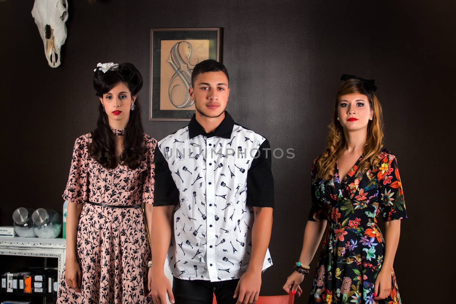 Two woman and a man posing on a vintage style retro clothing.