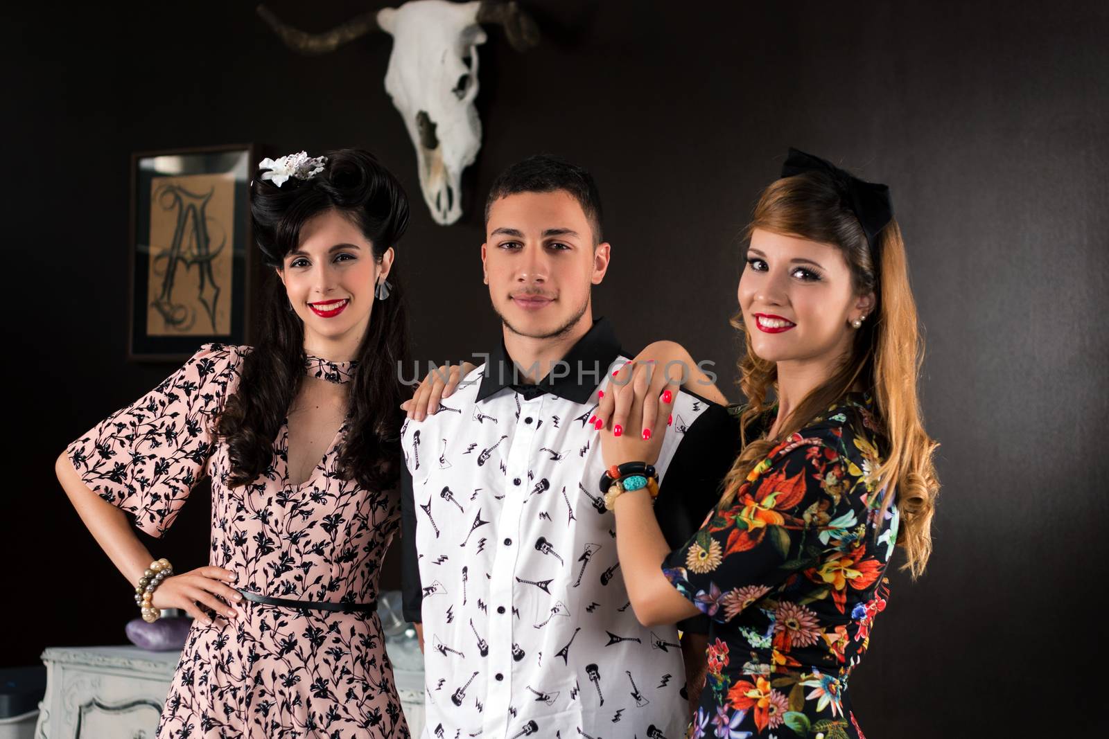 Two woman and a man posing on a vintage style retro clothing.