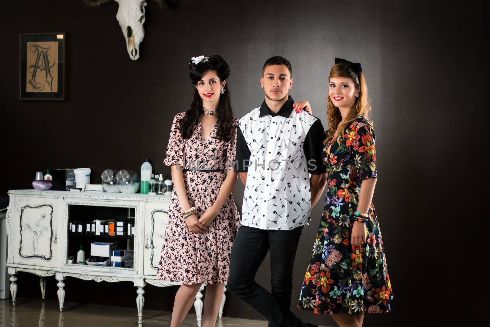 Two woman and a man posing on a vintage style retro clothing.