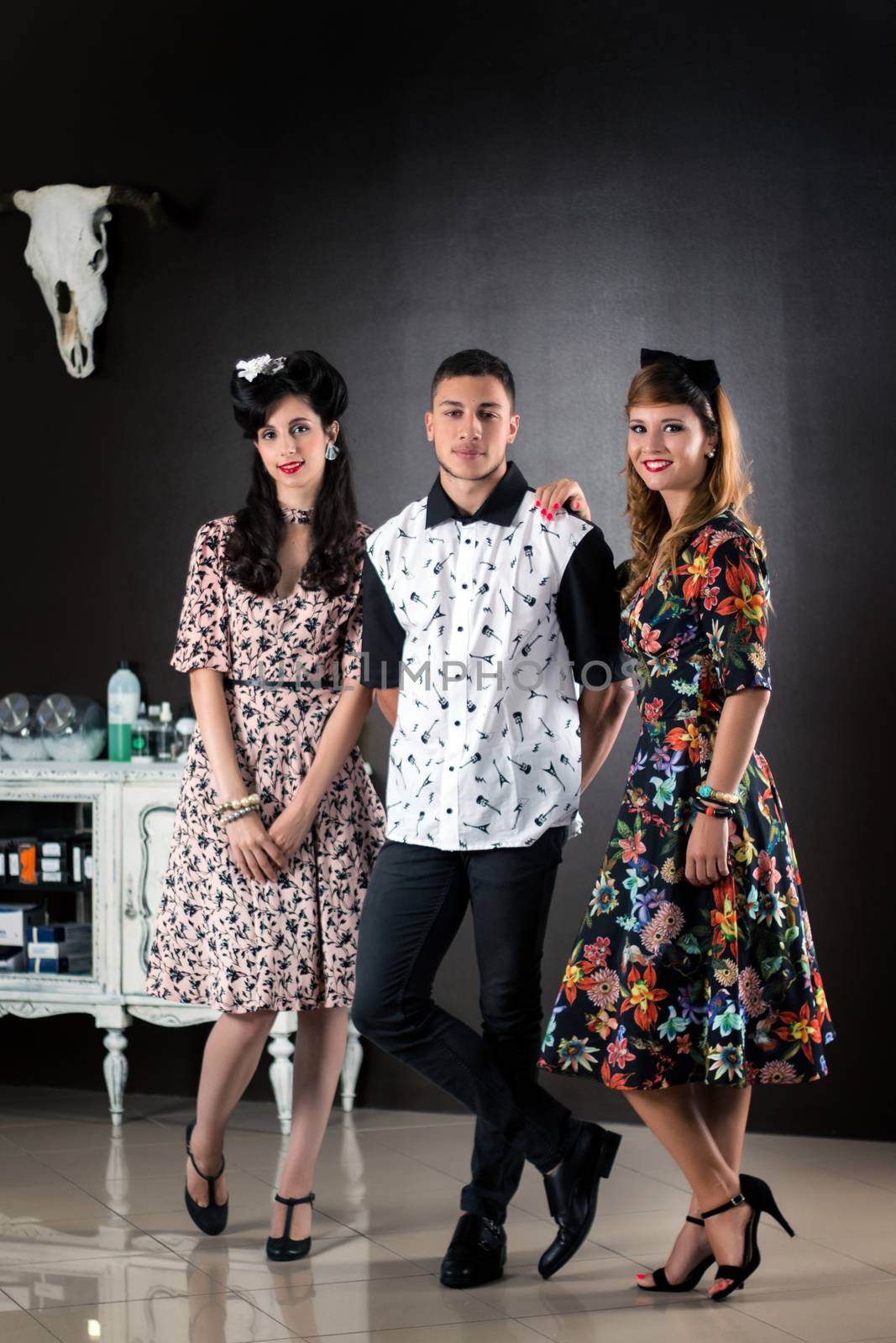 Two woman and a man posing on a vintage style retro clothing.