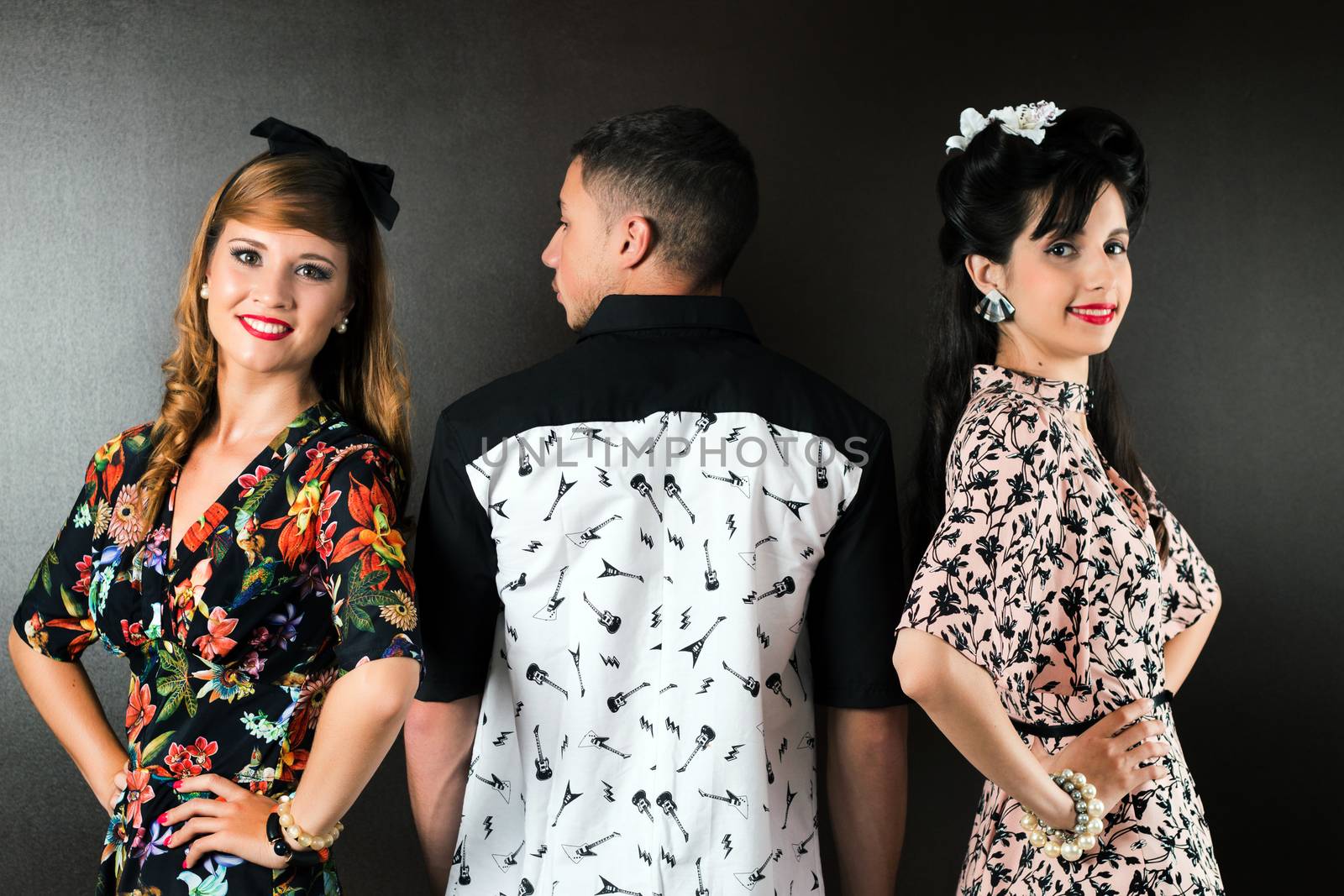 Two woman and a man posing on a vintage style retro clothing.