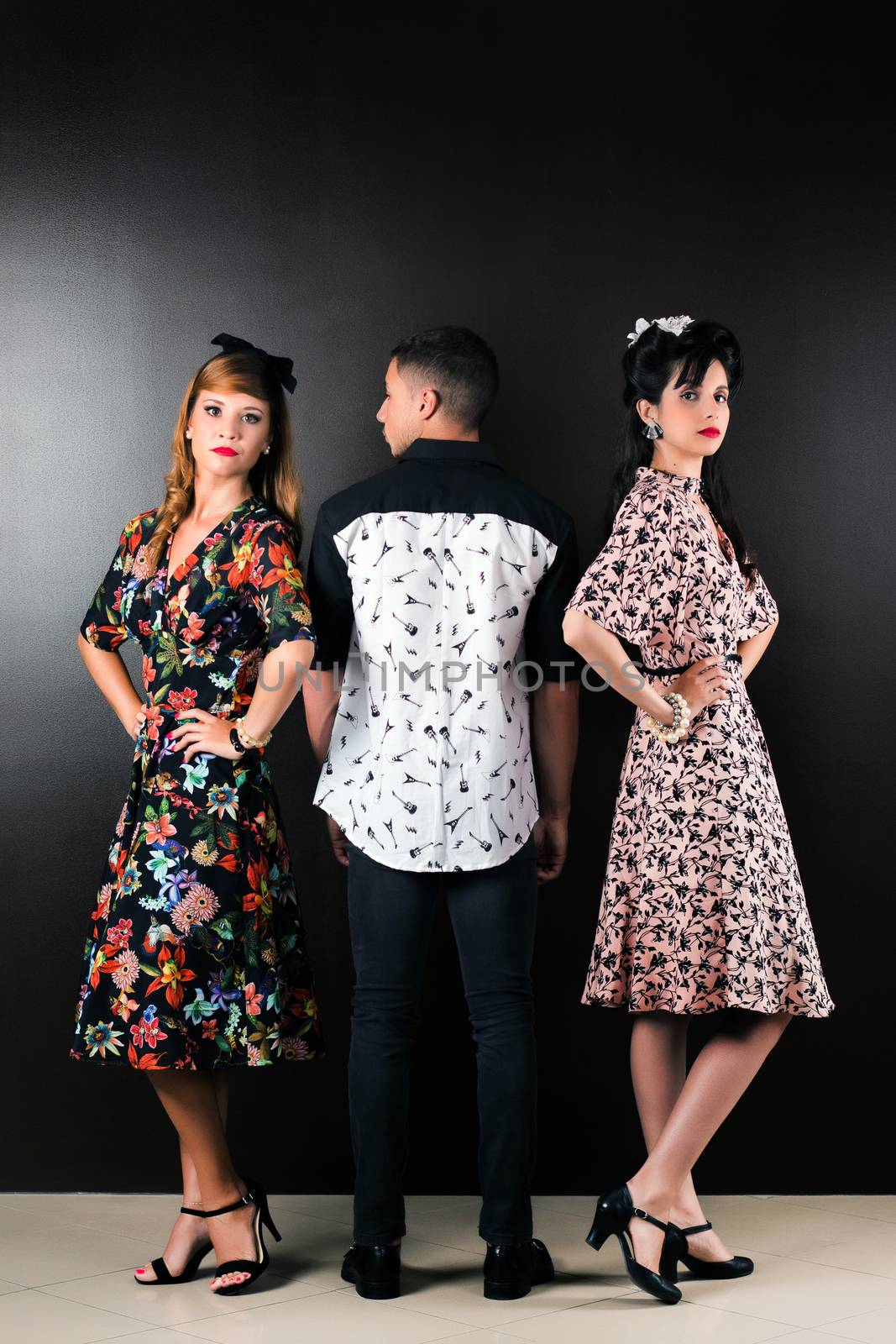 Two woman and a man posing on a vintage style retro clothing.