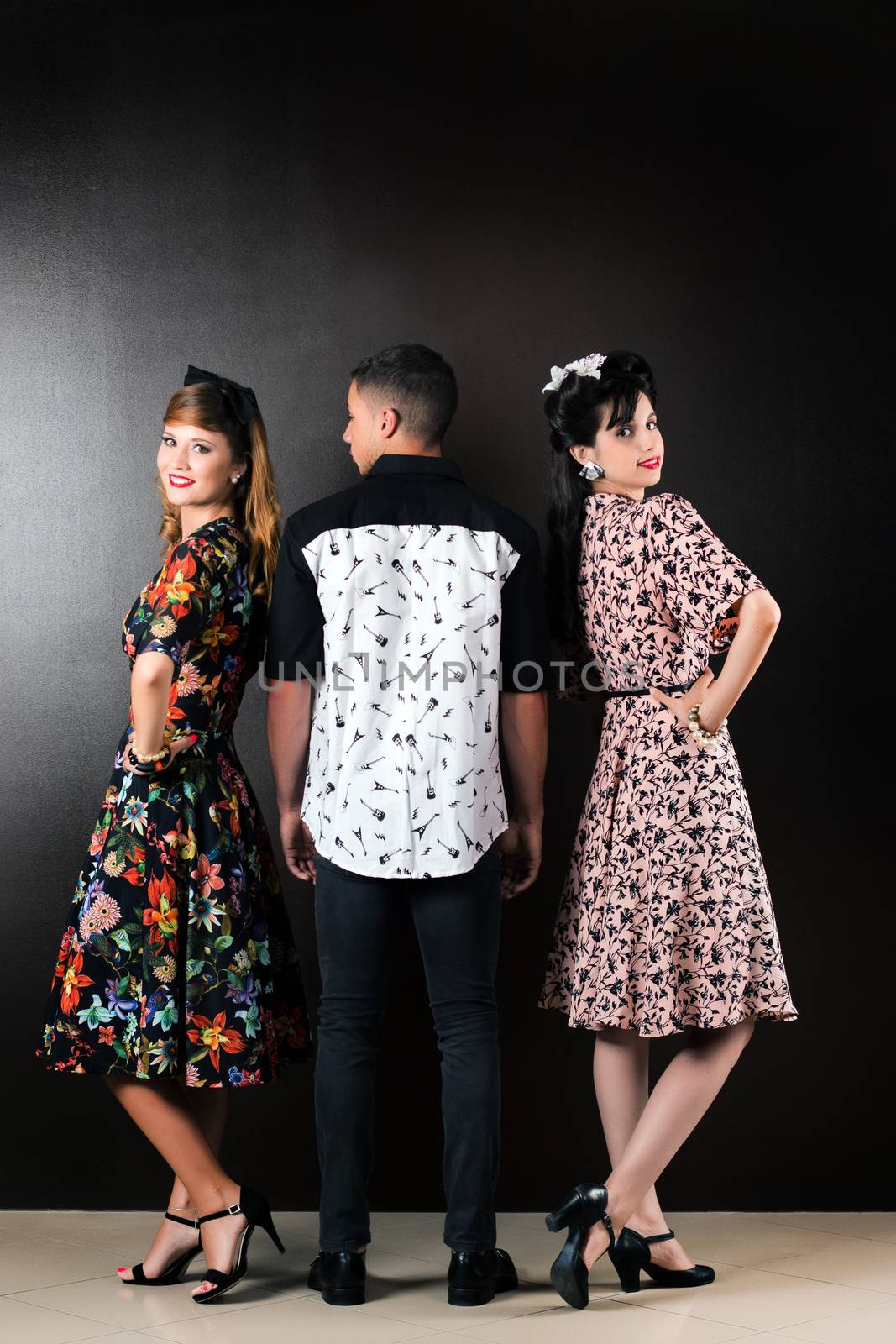 Two woman and a man posing on a vintage style retro clothing.