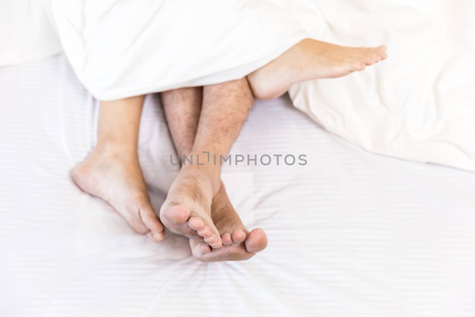 young sexy couples in love lying in bed in hotel, embracing on white sheets, close up legs, romantic mood