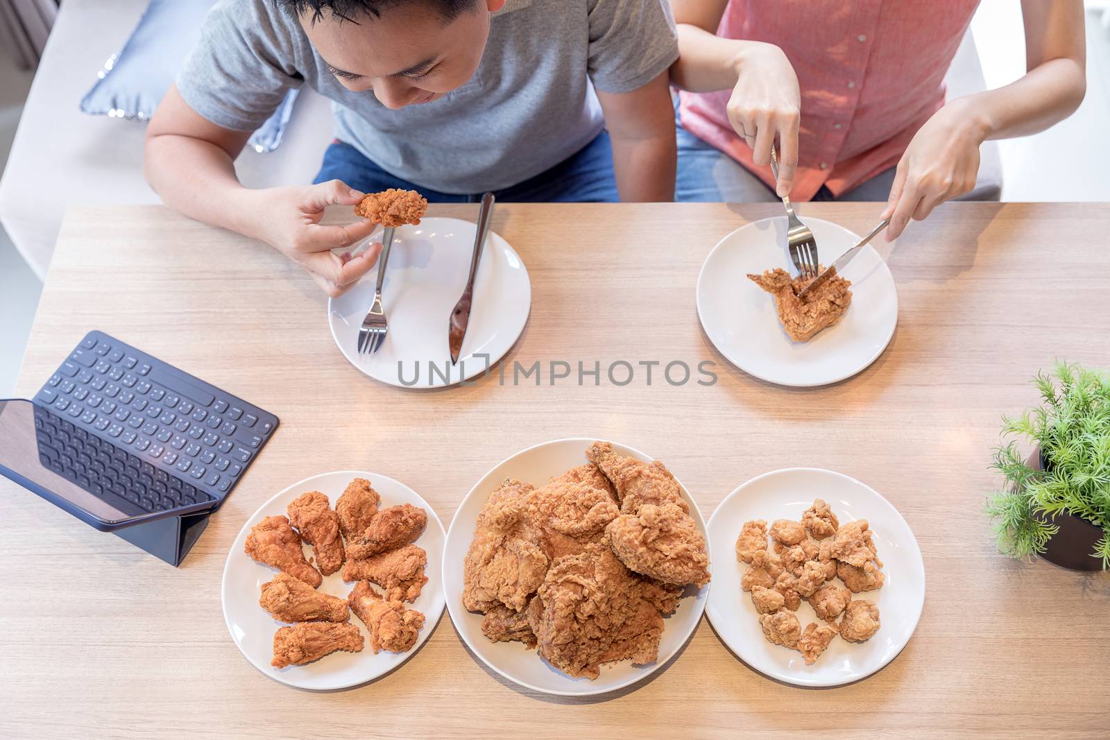 Young Asian Couples eating fried chicken together in living room of contemporary house for modern lifestyle concept Top View