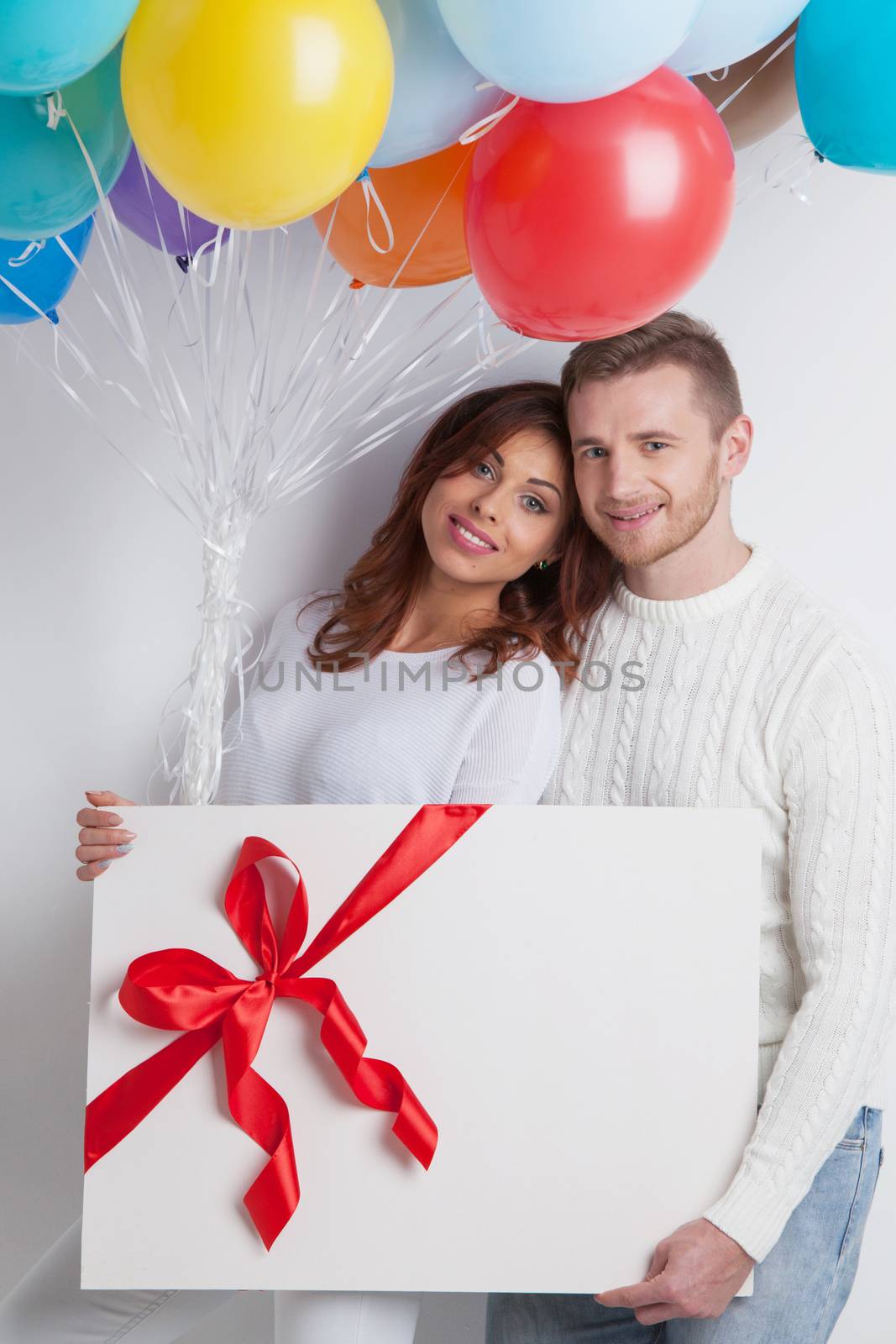 Young smiling couple with balloons and big gift box