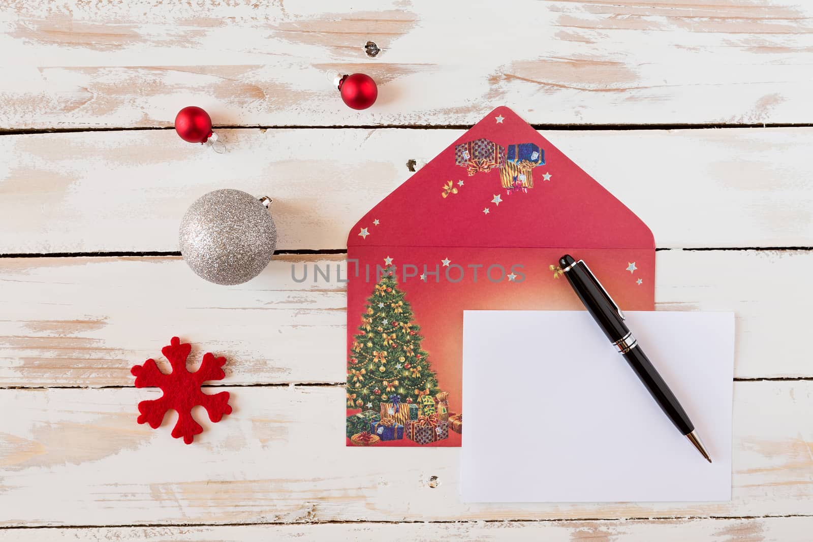Christmas letter and pen over a rustic wooden table with decorations