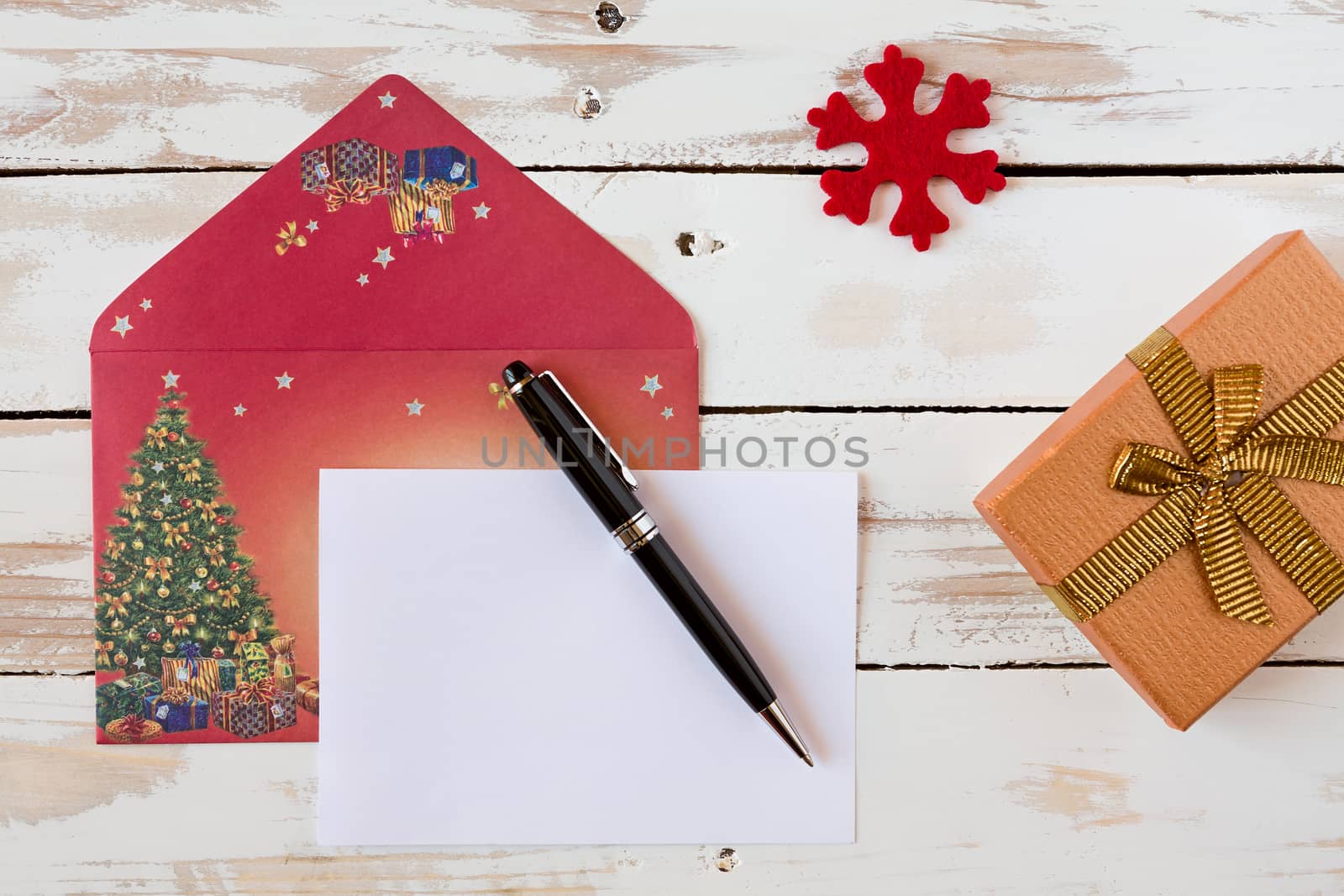 Christmas letter and pen over a rustic wooden table with present